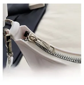 Close-up of a smooth silver metal zipper on a white crescent hobo shoulder bag