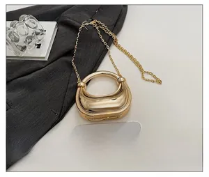 Detailansicht der glänzenden goldenen Mini-Acryltasche mit schicker Metallkette und Größenvergleich