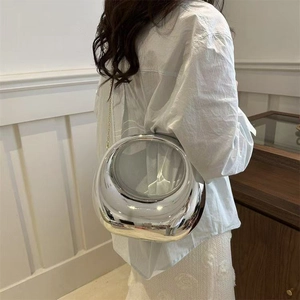 Détail du sac sphérique miroir argenté avec chaîne en métal porté par un mannequin