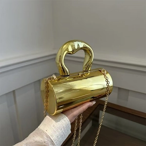Detail of a metallic gold cylindrical handbag with an artistic handle and gold chain strap