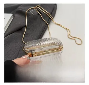 Detail of transparent acrylic clutch with gold snake chain and vertical stripes texture