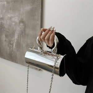 Close-up of a silver cylindrical handbag with metallic finish and chunky top handle