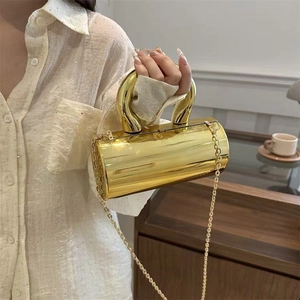 Close-up of golden cylinder chain bag featuring a mirror finish and U-shaped handle