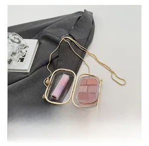 Detail of mini gold metal chain bag interior showing lipstick and eyeshadow storage