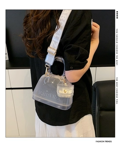 Detail view of transparent PVC jelly bag with mini purse and wide fabric shoulder strap