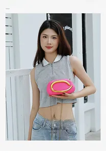 Dettaglio della mini borsa a secchiello magenta con manico a C dorato e tracolla