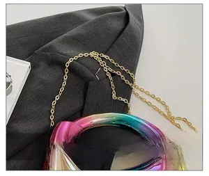 Detail of gradient acrylic evening bag with a sleek gold chain strap on grey blazer