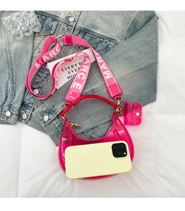 Close-up of pink jelly crescent bag with wide logo strap and mini coin purse detail
