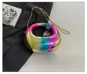 Iridescent round hollow evening clutch with gold chain shown beside a smartphone for size reference