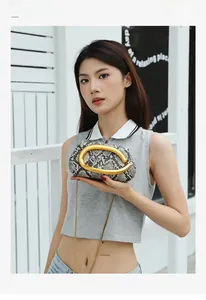 Detail of snake skin pattern handbag with large gold round handle and chain strap