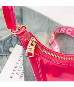 Detail of gold metal zipper and pink translucent jelly texture on crossbody bag