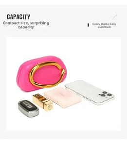 Dettaglio della mini borsa magenta con manico dorato a C ed elementi essenziali quotidiani