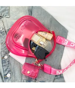 Detail view of pink transparent PVC jelly bag with wide jacquard strap and internal essentials