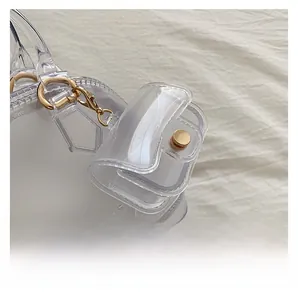 Detail shot of clear PVC jelly bag featuring golden D-rings and a matching mini pouch