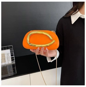 Oranje crossbodytas met gouden metalen boog en fijne goudkleurige ketting