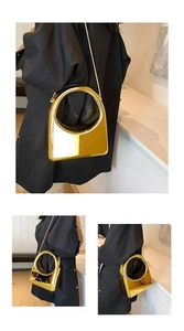 Detalle del bolso geométrico dorado con asa redonda hueca y cadena de metal fina