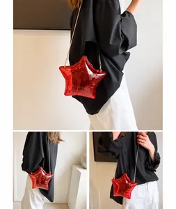 Detalle del bolso de acrílico rojo translúcido en forma de estrella con cadena de metal oro