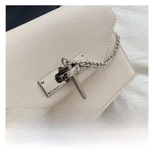 Detail of cream Saffiano faux leather texture with elegant silver twist lock and chain