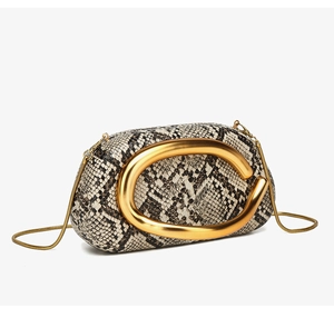 Detailed view of black and white snakeskin pattern and gold C-shaped metal clasp