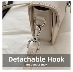 Detail view of detachable silver metal swivel hook on beige leather shoulder bag