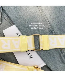 Detail of adjustable yellow and white striped nylon bag strap with gold metal buckle