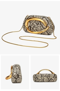 Detail view of snakeskin print clutch bag with bold gold C-shaped metal handle and chain