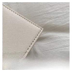 Detailed macro view of Saffiano leather texture and fine stitching on white Kelly bag