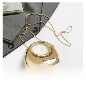 Detail of mirror gold metallic acrylic handbag showing glossy surface and chain strap