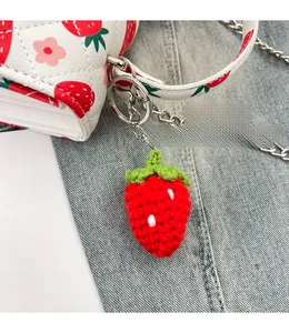 Détail d'un pendentif fraise au crochet sur un sac à bandoulière matelassé à fleurs