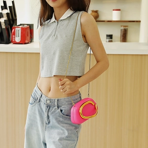 Mini borsa a secchiello rosa acceso con grande anello dorato indossata da una modella