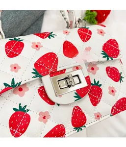 Détail du fermoir rotatif argenté sur sac matelassé aux fleurs et fraises imprimées
