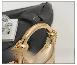 Detail view of the polished golden metal handle and fine chain of the elegant evening bag