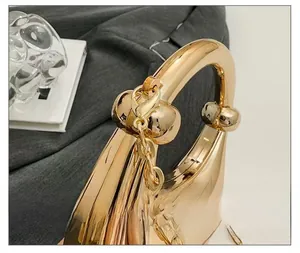 Detailed close-up showing high-quality polished gold metal handle and chain on the evening bag