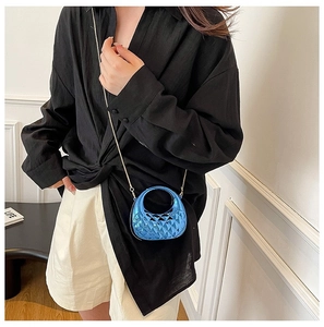 Macro shot of electric blue quilted mini bag with round handle and metal chain strap