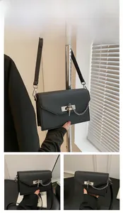 Detail view of black crossgrain leather handbag with silver twist lock and chain strap