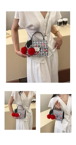 Détail du sac à carreaux avec imprimé cerises, chaîne en métal et pompons rouges