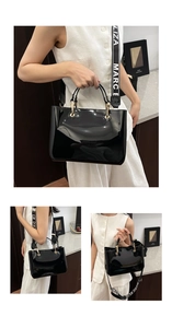 Detail view of glossy black patent leather tote with gold hardware and wide logo strap