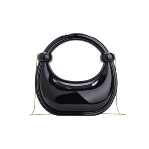 Detail view of glossy black acrylic crescent bag with chic gold chain strap