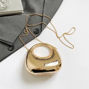 Minimalist gold metallic crescent bag with top handle and chain strap on grey blazer