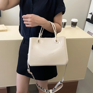 Chic cream patent leather tote bag with wide logo strap and elegant gold hardware
