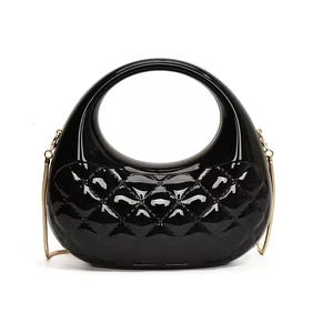 Close-up of black quilted patent leather hobo bag with gold chain strap detail