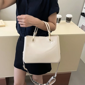 Chic cream patent leather tote bag with gold hardware and stylish lettered wide strap