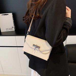 Elegant off-white faux leather crossbody bag with metal buckle on a black suit