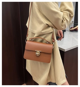 Detailed view of caramel lychee texture leather handbag with golden twist lock on trench coat