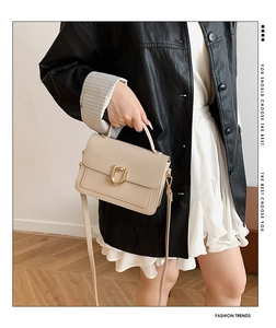Detail view of cream pebble leather bag with gold U-shaped hardware and top handle