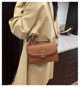 Detail of caramel brown textured leather crossbody bag styled on a trench coat model