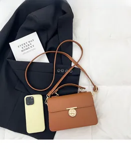 Détail d'un sac à main en cuir marron à motif litchi avec boucle de verrouillage dorée