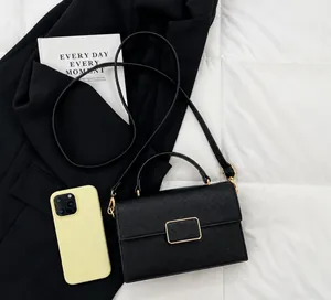 Detail of black lychee grain leather handbag with gold square lock and shoulder strap