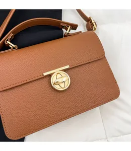 Détail du fermoir en T doré brillant et des coutures serrées sur le cuir de couleur caramel