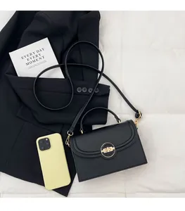 Détail du sac à main noir en cuir grainé avec fermoir anneau doré sur surface matelassée